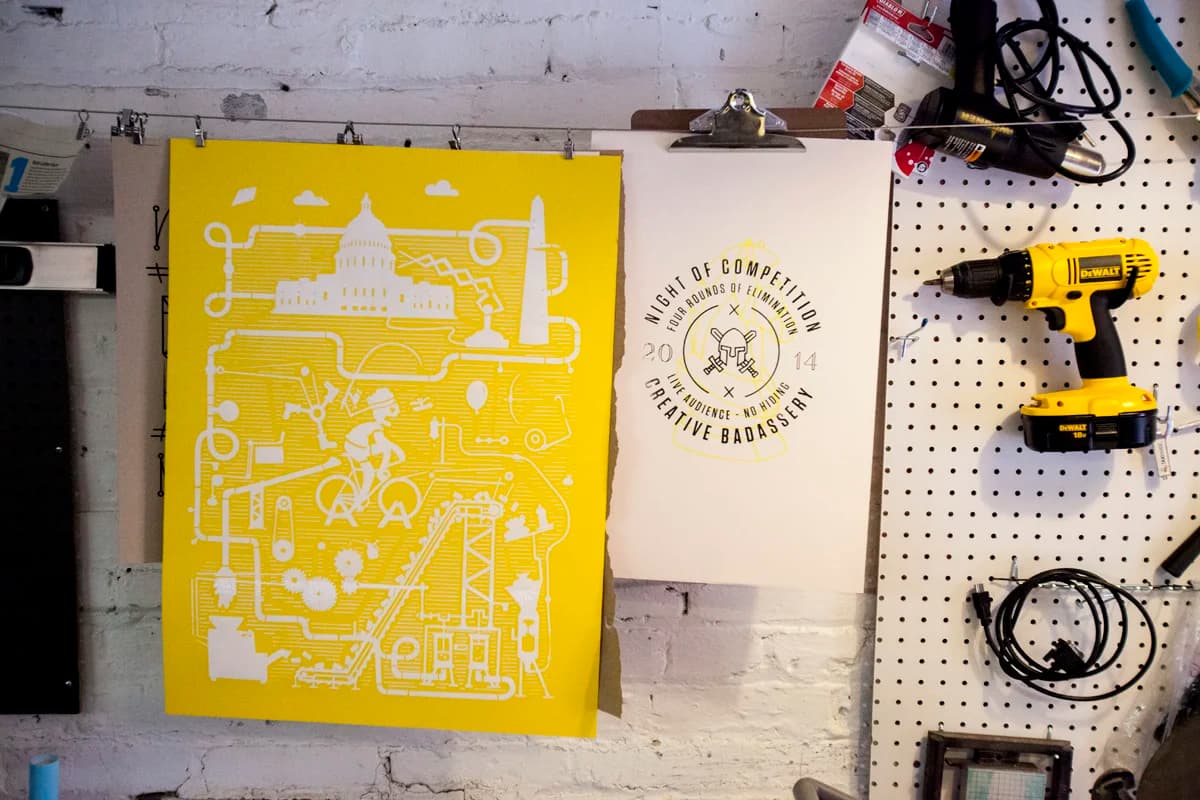 A yellow Artcrank DC poster drying alongside its proof print.