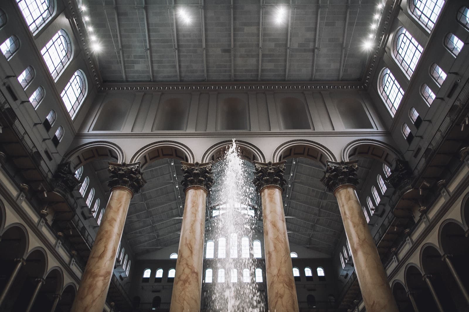 National Building Museum interior shot from below, marble columns flanking the central fountain shaft.