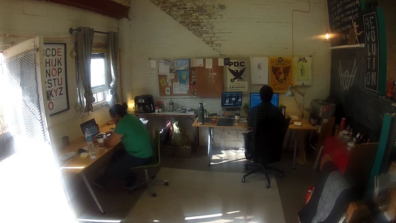 Inside the DC carriage house in 2014, with a letterpress, brick walls, and an ABC letter poster pinned above the desks.