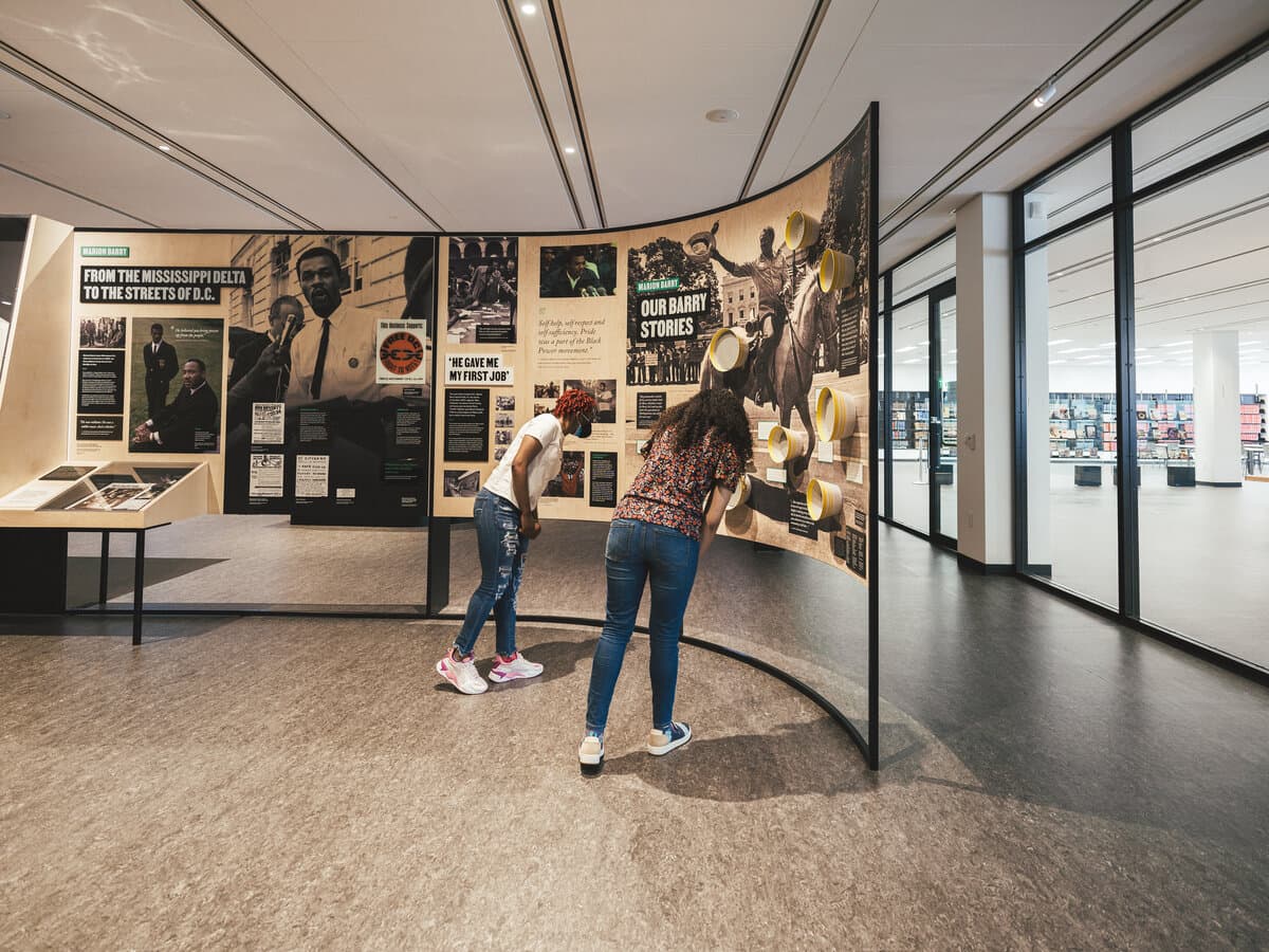 MLK Memorial Library exhibition, the curved Mississippi Delta to the Streets of D.C. wall with visitors reading the Our Barry Stories panels.