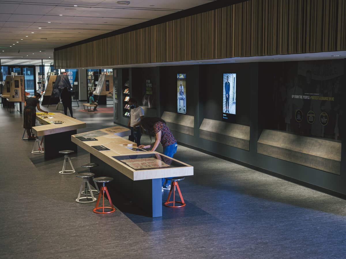 MLK Memorial Library exhibition, the Up From the People masthead with stool-height reading tables in the foreground.