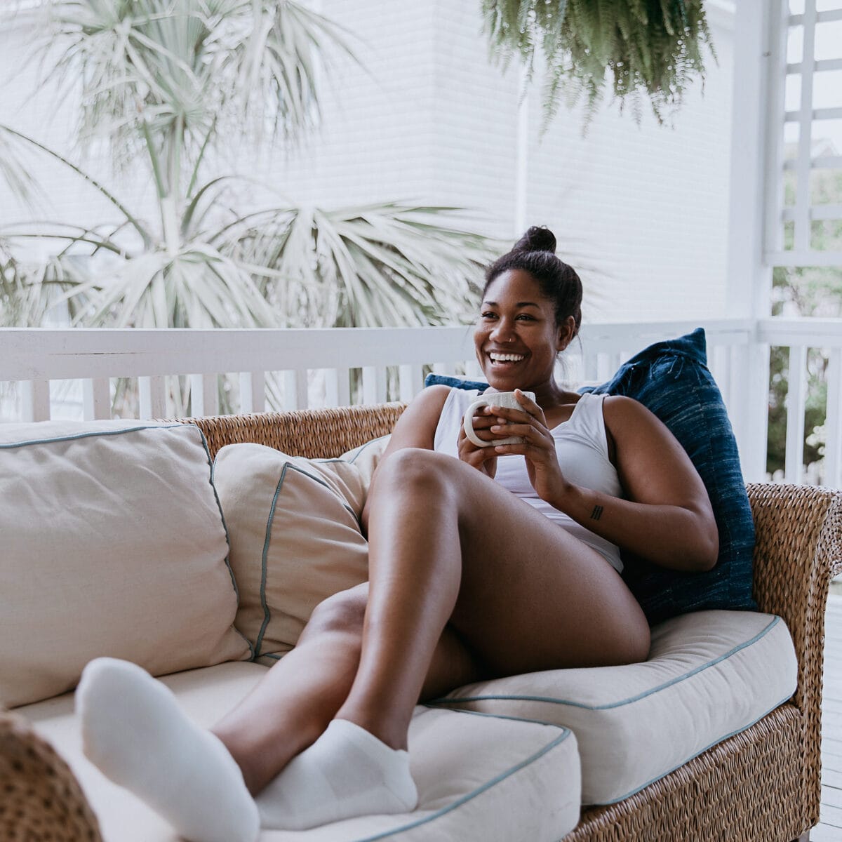 Creator photograph: a woman on a porch sofa in a white Boody cami