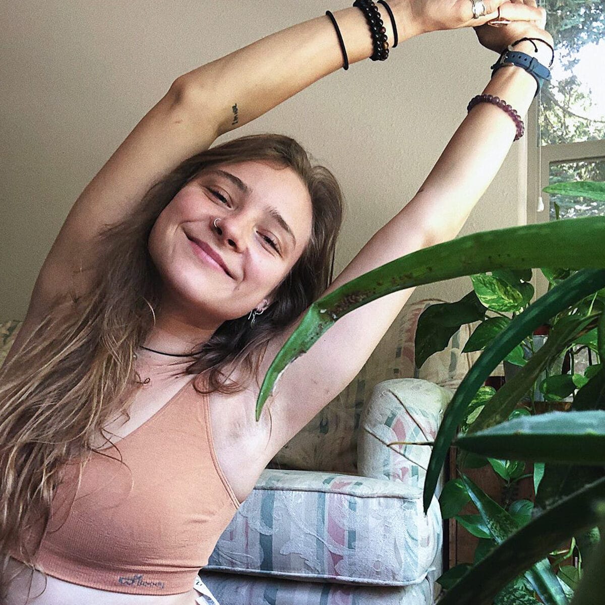 Creator photograph: a woman stretching in a peach Boody bra beside a houseplant