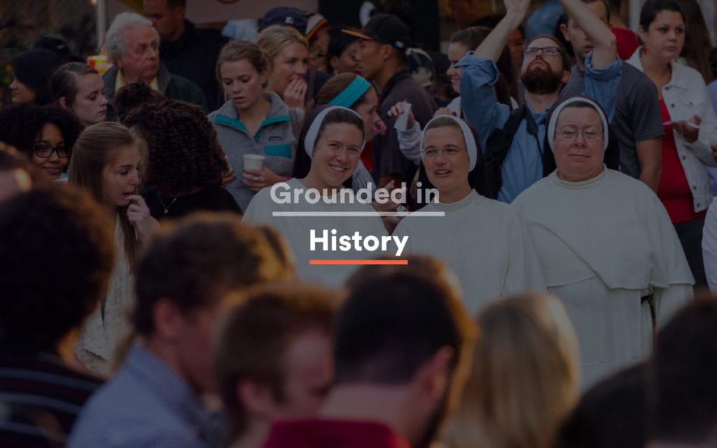 Religious procession with three nuns in habit moving through a busy diverse DC crowd, with "Grounded in History" set in compressed sans white over the photograph