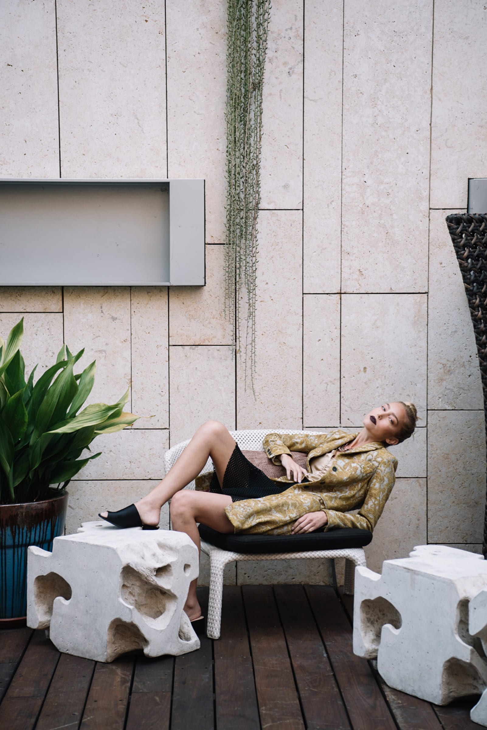 Man reclining on a terrace chair between carved stone stools