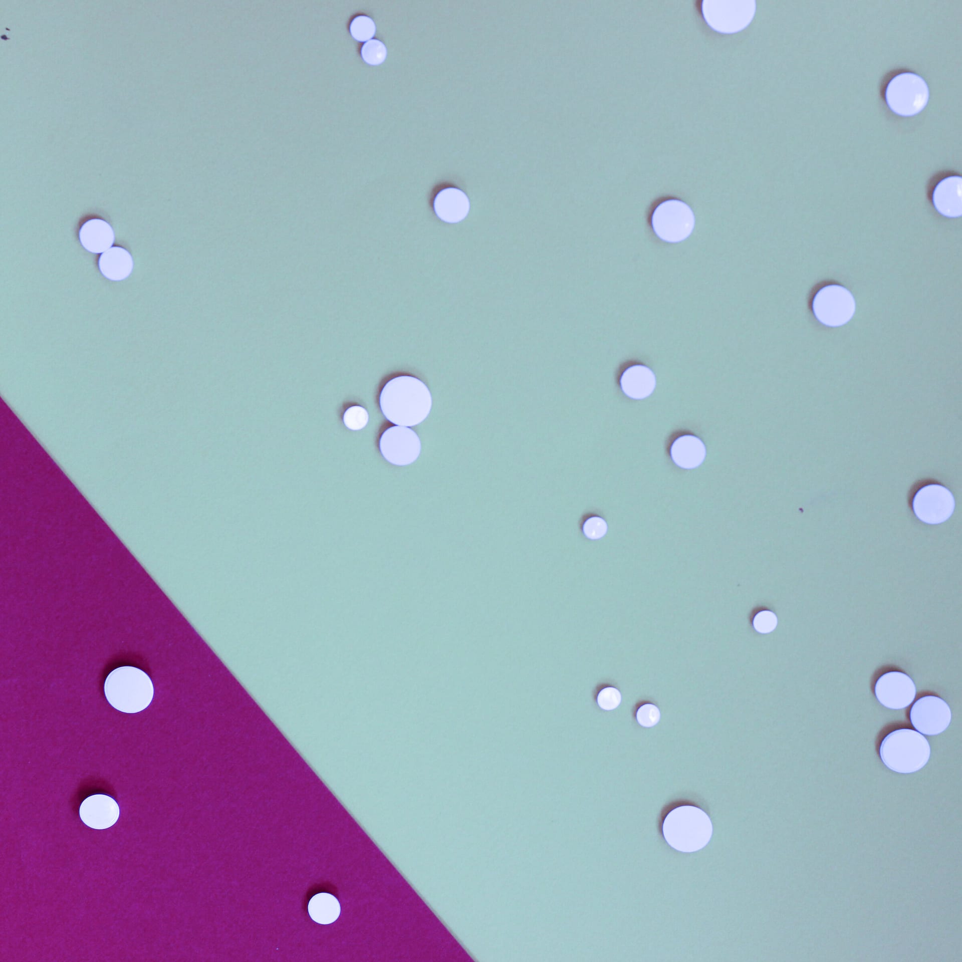 White drops on pale blue and magenta paper