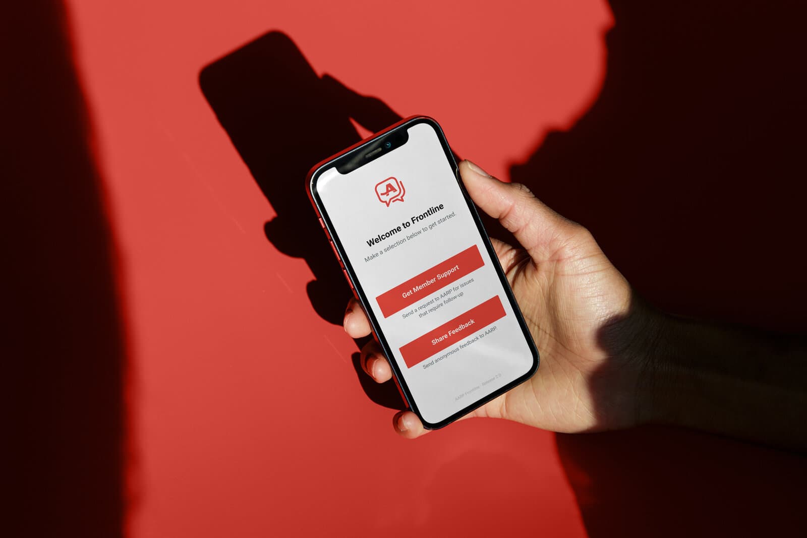 Frontline app welcome screen on a phone held against a red ground