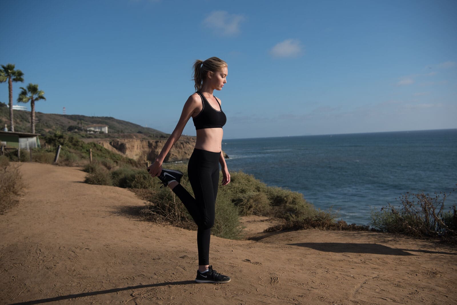 A runner stretching on the coastal path above the Pacific
