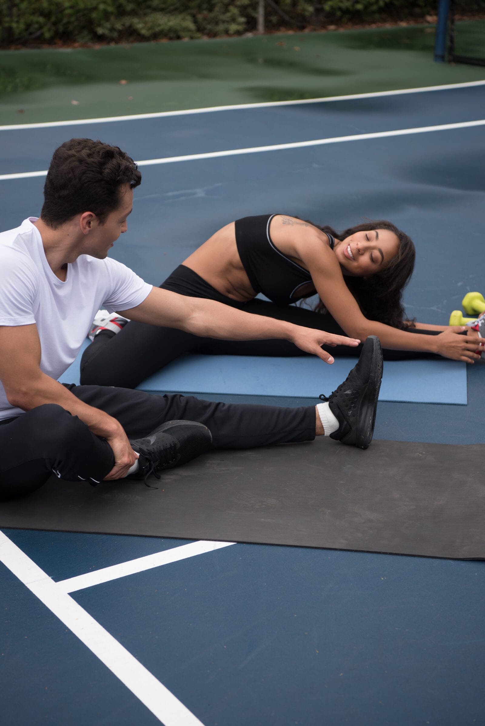 Two of the cast stretching on a mat, courtside