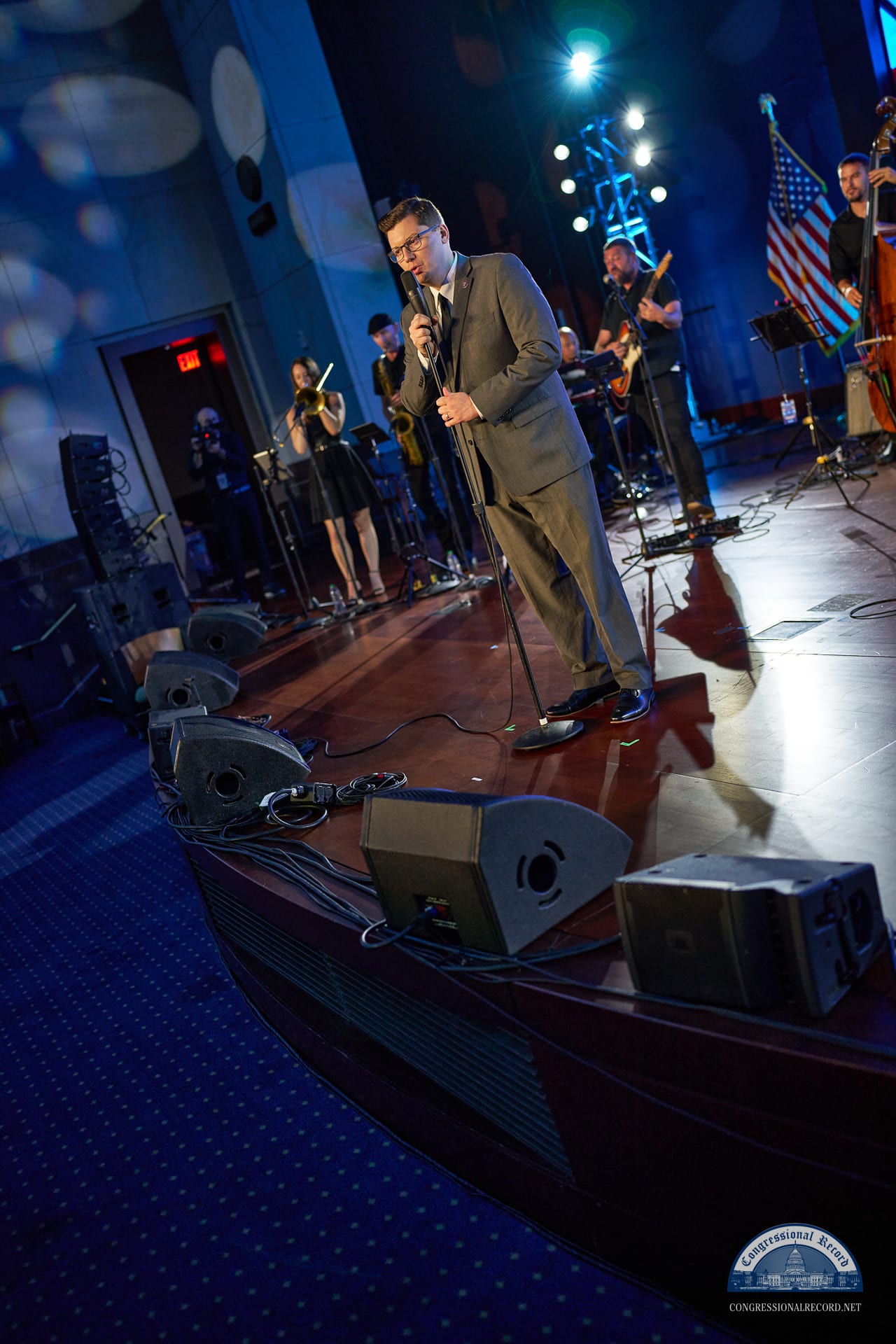 A performer on stage with the band, under red and blue light
