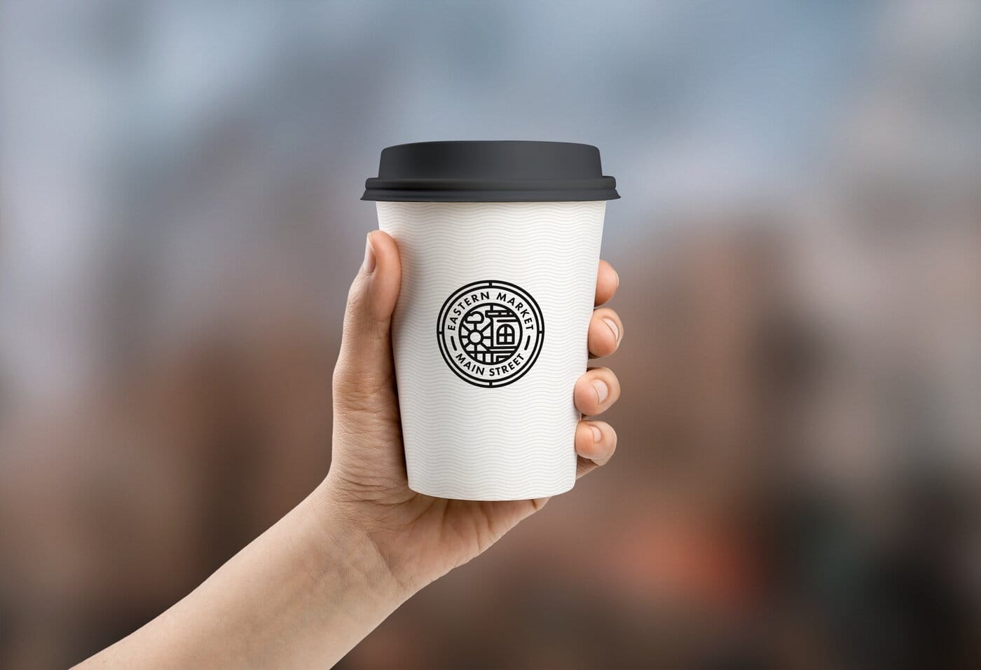 Coffee cup with the medallion mark, held in hand