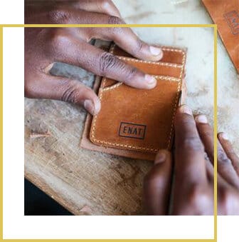 Hands pressing the ENAT stamp into a leather wallet