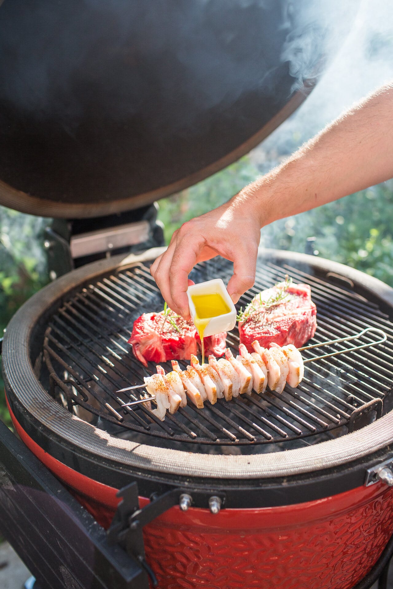 Hand seasoning a steak on the kamado with a small yellow cup