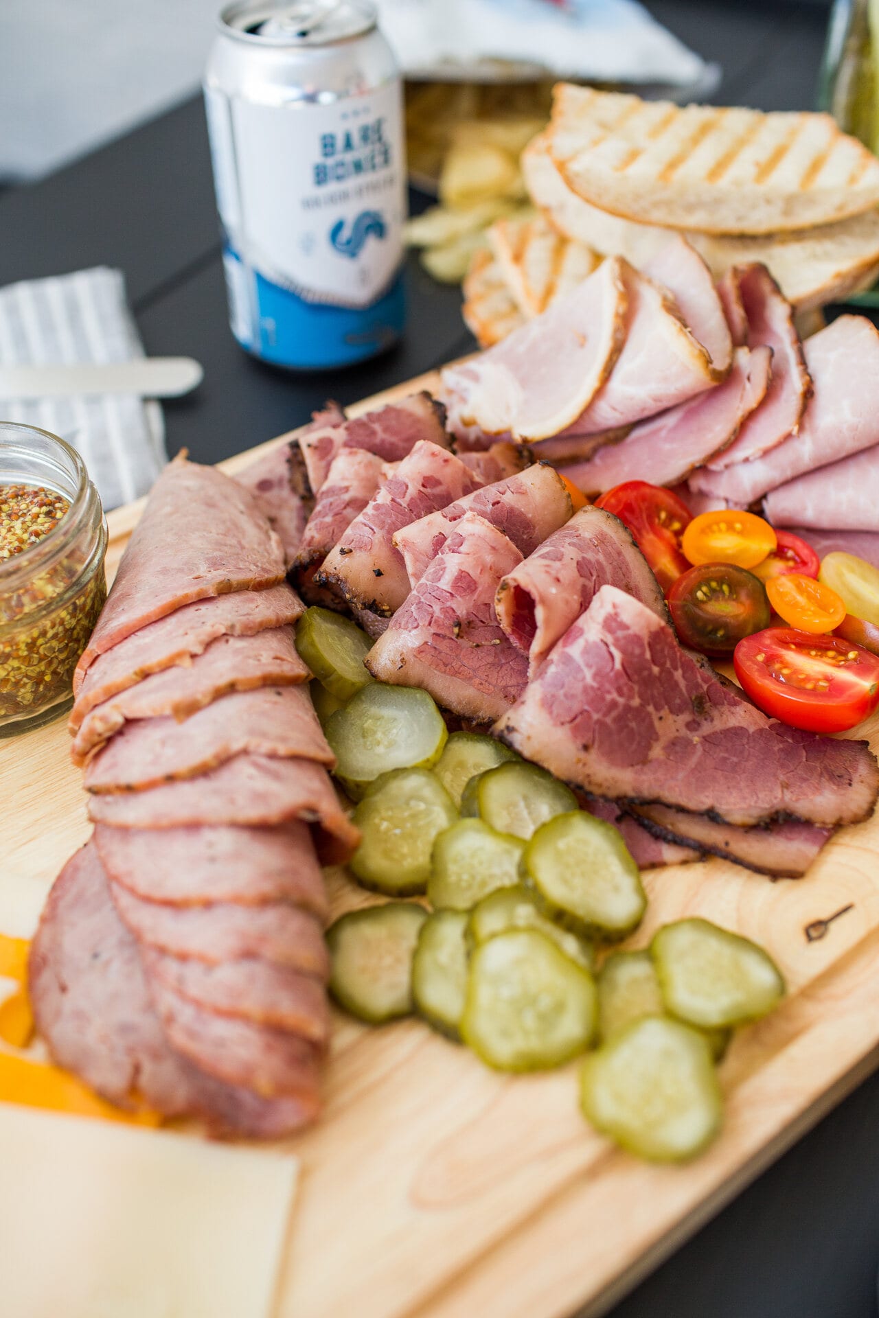 Sliced ham, pickles, and tomatoes on a board