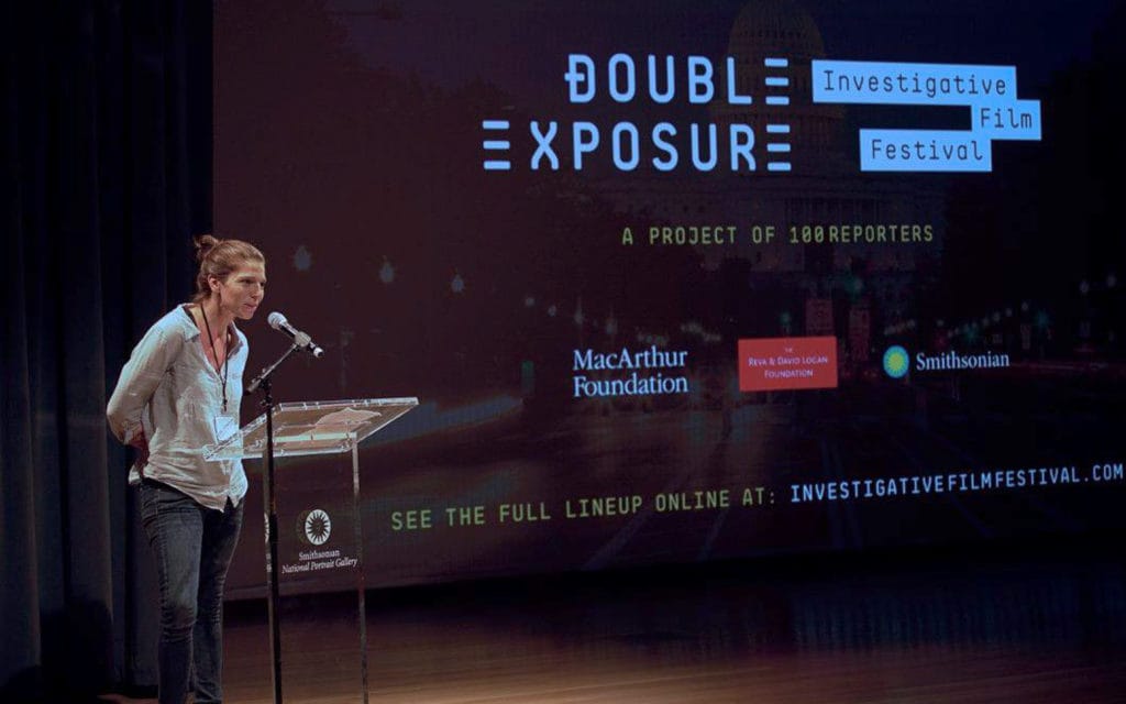 A speaker at the podium in front of the festival screen